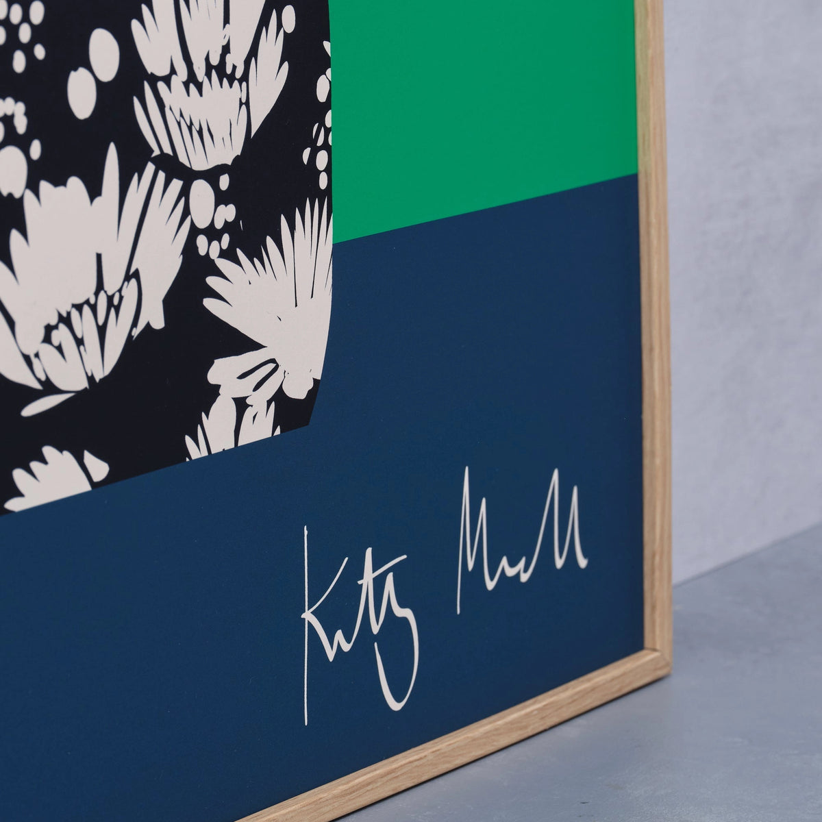 Close-up detail of the Daisy Vase fine art print by Kitty McCall showing the artist's signature on the navy base with the black and white daisy-patterned vase