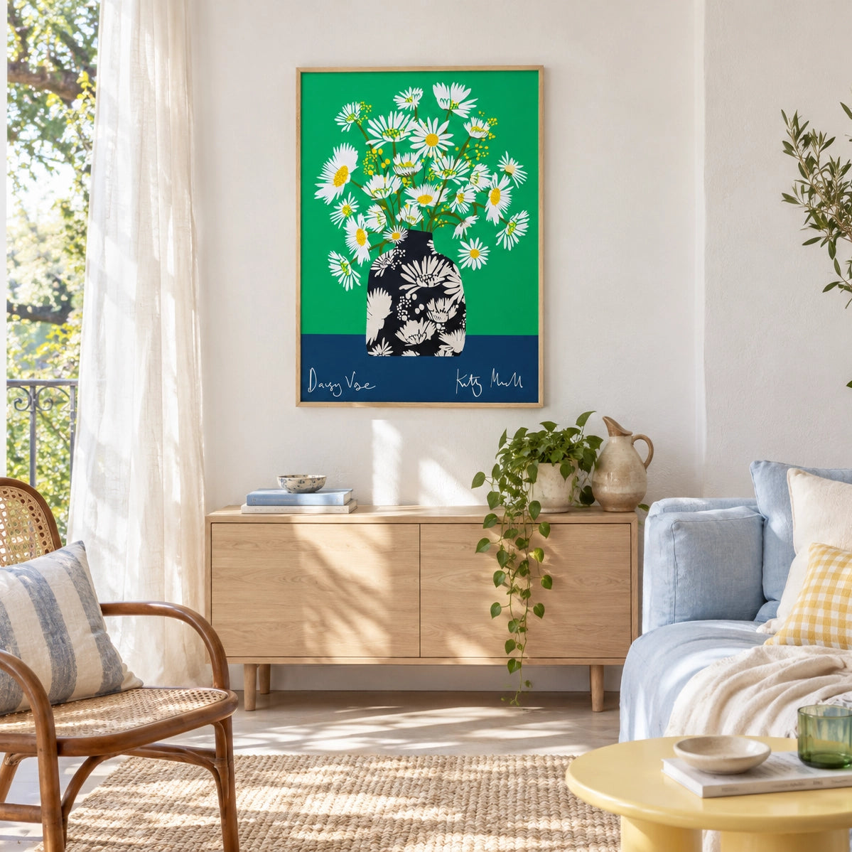 Daisy Vase fine art print by Kitty McCall in a natural oak frame, hung above a light oak sideboard in a bright, airy living room with rattan chair, blue sofa and trailing houseplant