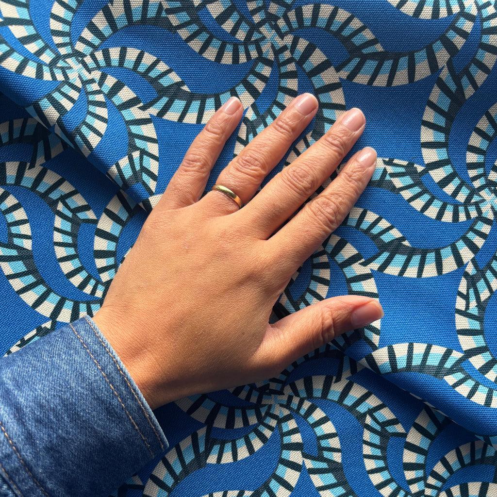 Hand touching blue fabric with white geometric pattern