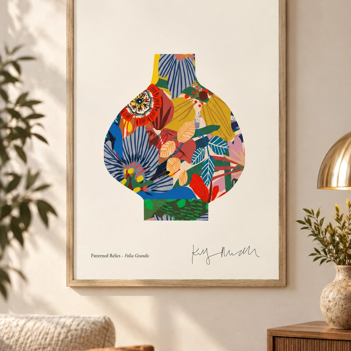 A framed art print featuring a colorful abstract vase illustration on a white background, hanging on a beige wall in a styled living room with a sofa, plant, and lamp.