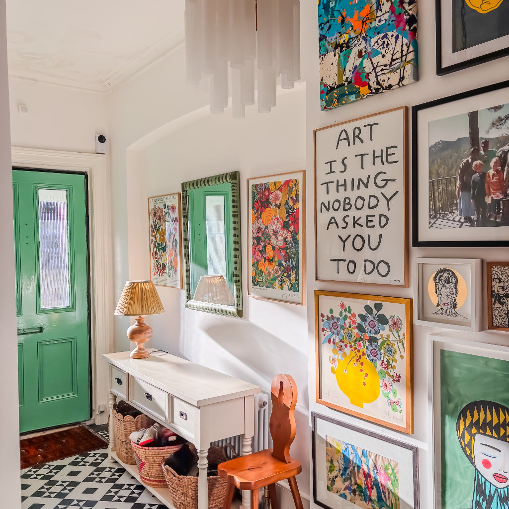 Colorful art gallery in a room with a green door and patterned floor.