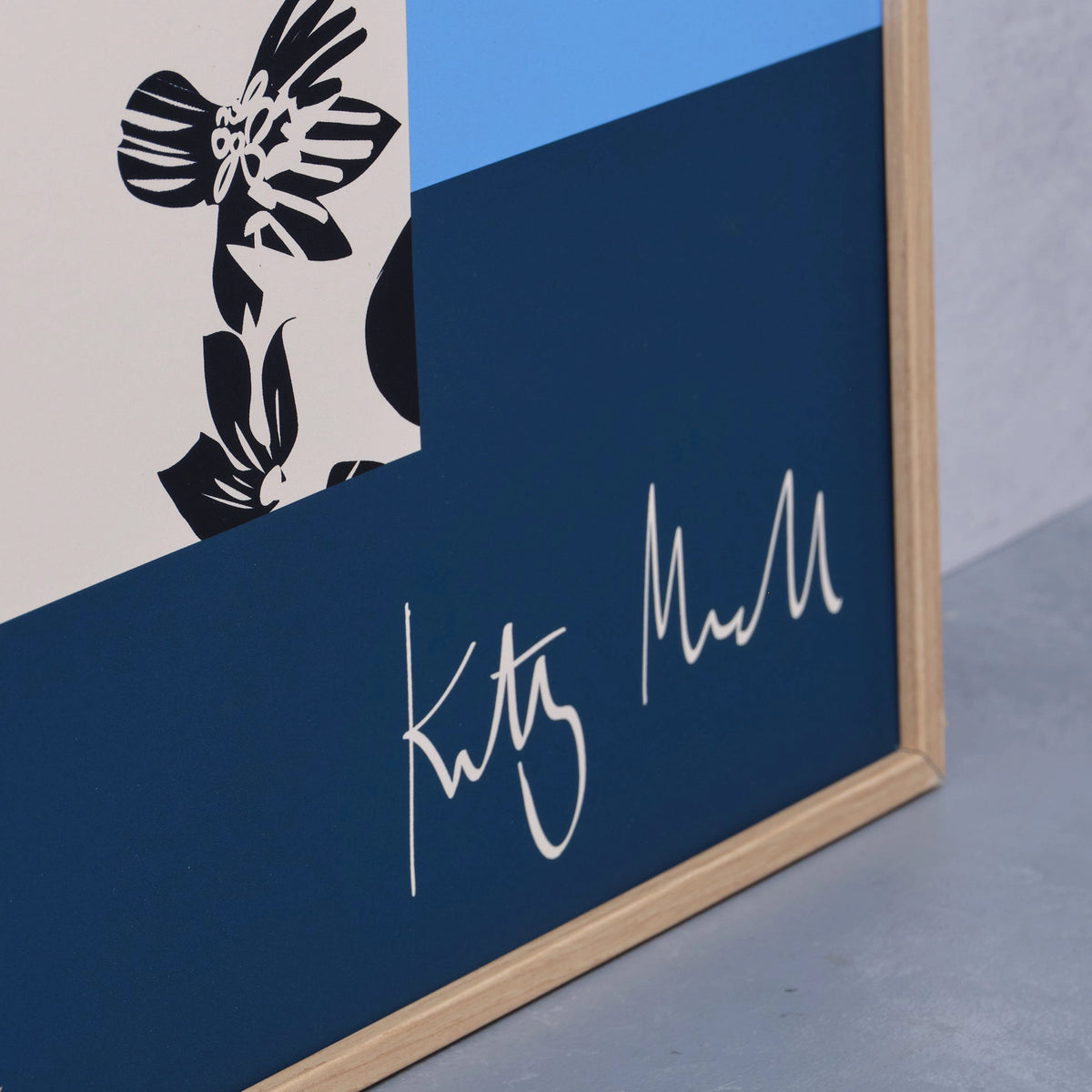 Close-up detail of the Pansy Vase fine art print by Kitty McCall showing the artist's signature on the navy base with the patterned black and white vase