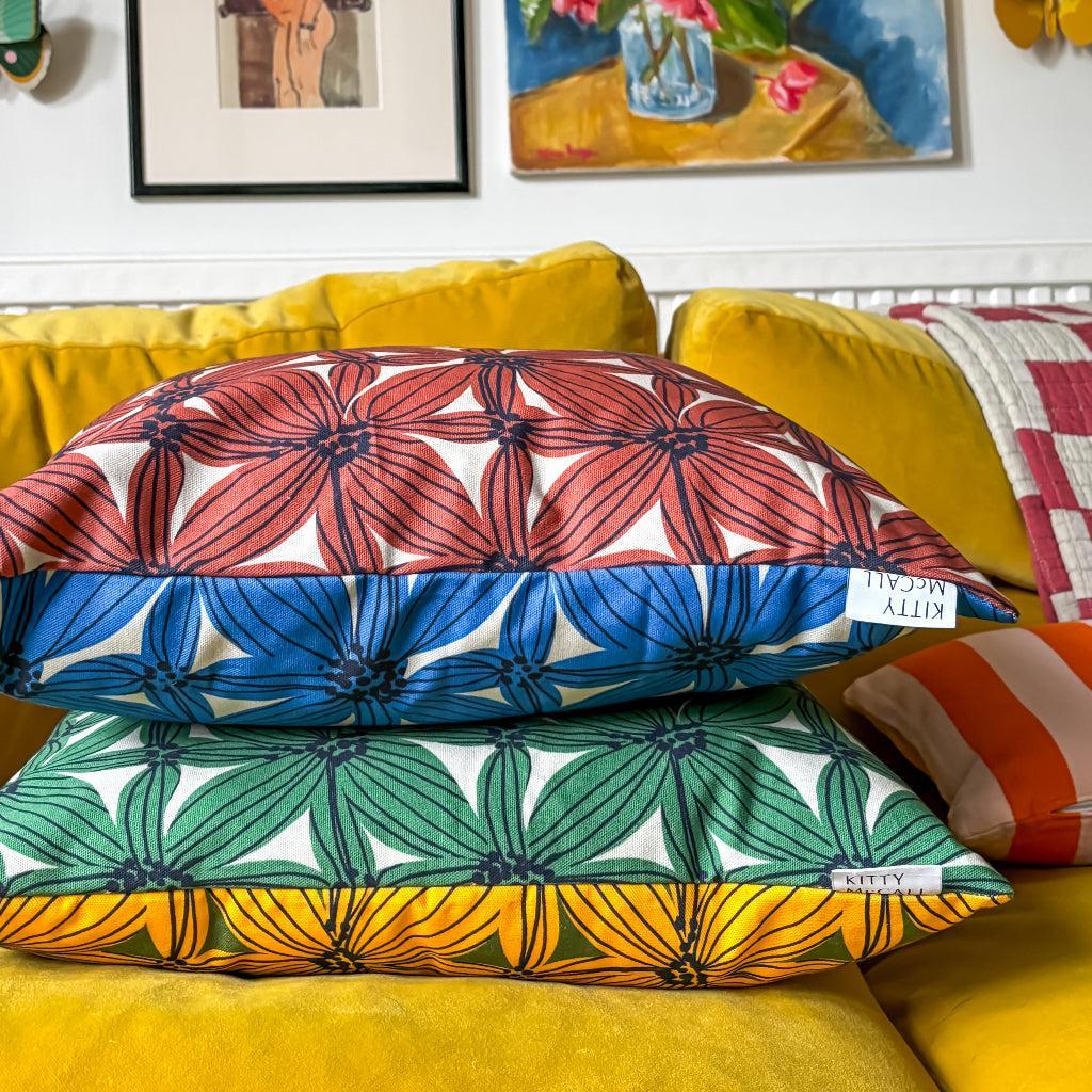 Colorful pillows with floral patterns on a yellow couch, surrounded by framed artwork.