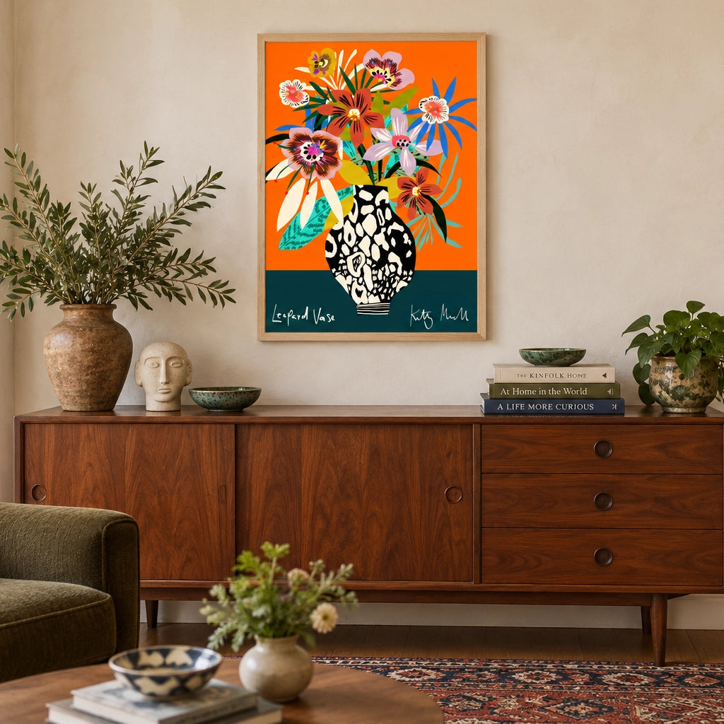 Leopard Vase fine art print by Kitty McCall in a natural oak frame, hung above a mid-century walnut sideboard in a warm living room styled with olive armchair, ceramic vessels and stacked books