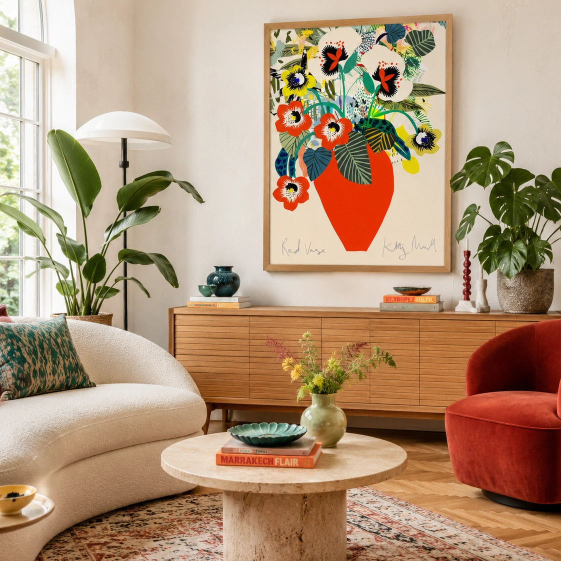Red Vase fine art print by Kitty McCall in a natural oak frame, hung above an oak sideboard in a bright living room with arched window, boucle sofa, terracotta armchair and large tropical houseplants