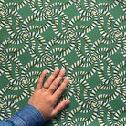 Hand touching a green fabric with a geometric pattern