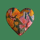 Colorful floral-patterned fabric heart on a green background