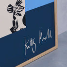 Close-up detail of the Pansy Vase fine art print by Kitty McCall showing the artist's signature on the navy base with the patterned black and white vase